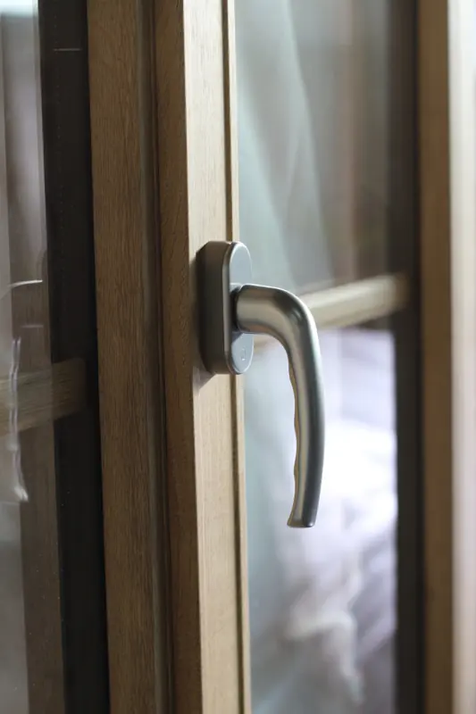 Gros plan sur la poignée aspect inox d'une fenêtre RFP® FPEE en décor chêne mat